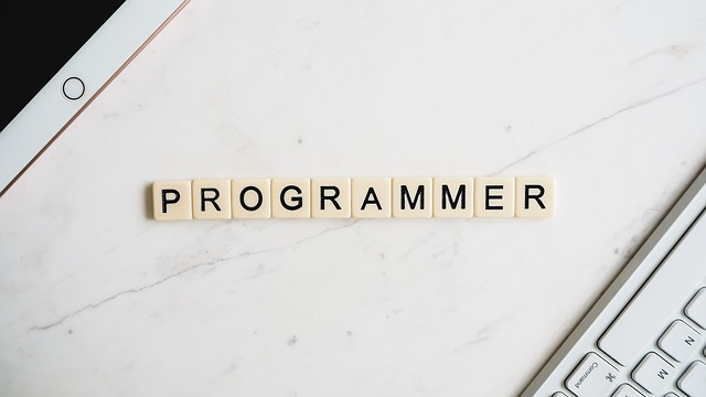 Programmer workspace with wooden letter blocks spelling PROGRAMMER